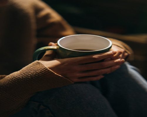 Close up of hands resting comfortably with a cup of coffee on a terrace